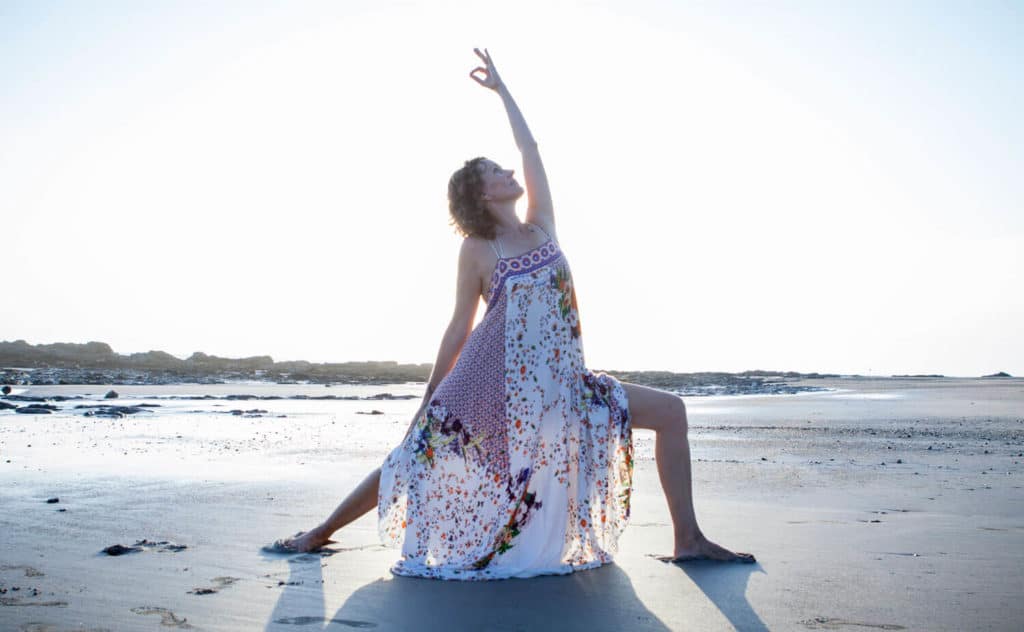 Dagmar doing warrior II pose on the beach